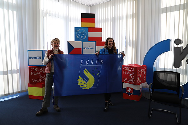 Sonja Heinrich, Mitglied des Executive Committee von Hofmann Personal, hält gemeinsam mit einer weiteren Frau eine EURES-Flagge beim EURES-Jahrestreffen 2026.