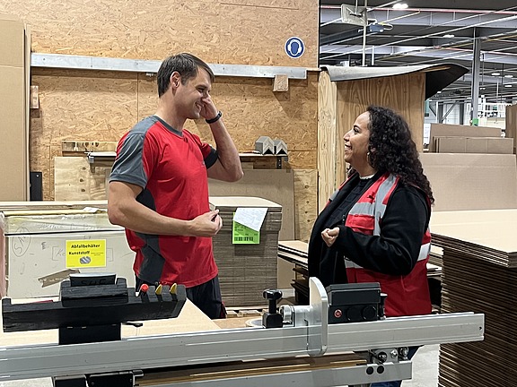 Mitarbeiter im Gespräch mit einer Hofmann-Personalbetreuerin in der Produktionshalle des Verpackungsherstellers