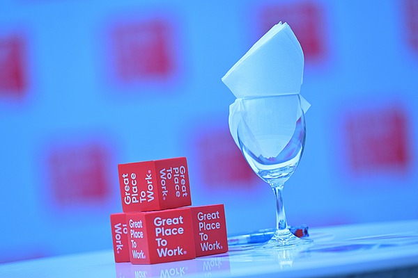 Kleine rote Great-Place-To-Work-Würfel neben einem edlem Glass.