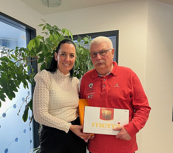 Einem Mitarbeiter wird zum Ruhestand ein Geschenk überreicht, symbolisch für Zusammenhalt und Teamgeist bei Hofmann Personal.